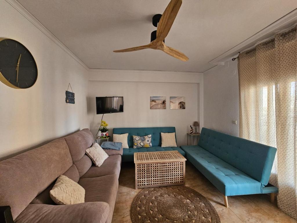 sala de estar con sofá azul y ventilador de techo en Apartamento en Primera Línea de Playa y Muy Céntrico, en Miramar