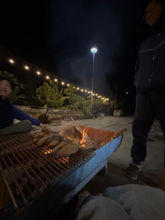 a person cooking food on a grill at night at Nhà gỗ Mộc châu Panorama in Mộc Châu