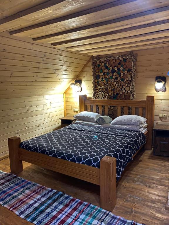 ein Schlafzimmer mit einem Bett in einem Holzzimmer in der Unterkunft Номер 6 Садиба У Ані in Synewyrska Poljana
