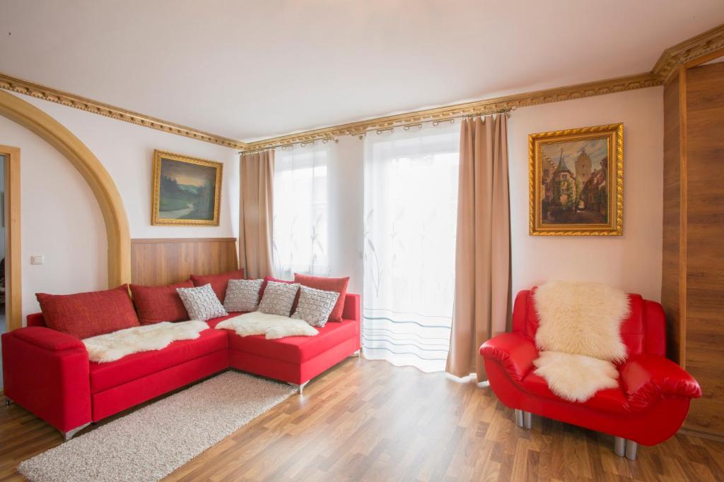 ガルミッシュ・パルテンキルヒェンにあるGolden GaPa Central Family Apartment 8のリビングルーム(赤いソファ、椅子2脚付)