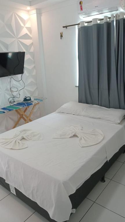 a bed with white sheets and a television in a room at Melhor custo benefício in Belém
