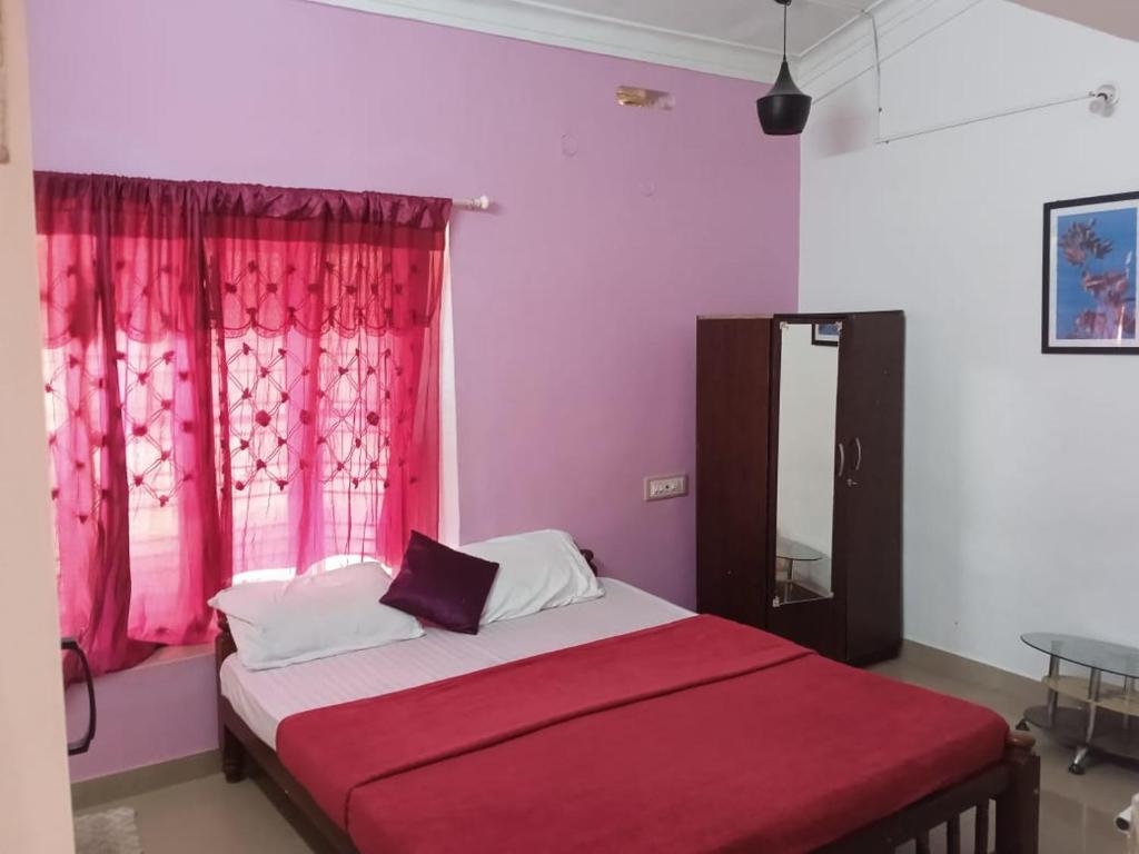 a bedroom with a bed with a red blanket and a window at Balkis homestay in Madikeri