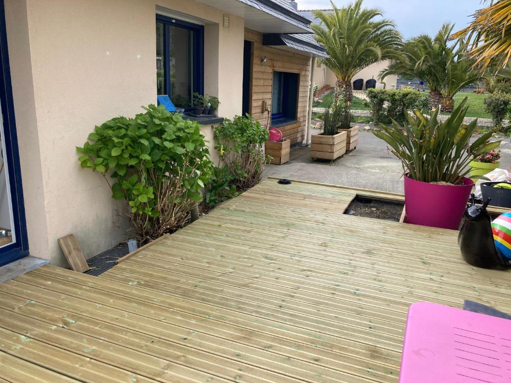 une terrasse en bois à l'extérieur d'une maison ornée de plantes dans l'établissement lesmainsdelange, à Concarneau