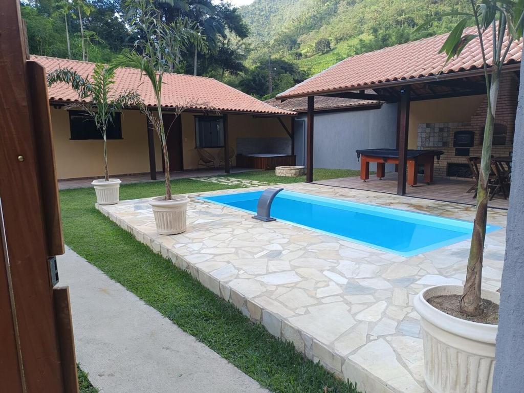 a house with a swimming pool with a table and trees at Meu canto em Lumiar in Nova Friburgo