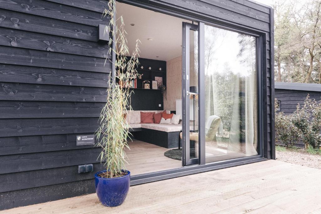 ヌンスペートにあるUltiem ontspannen in luxe en design ingericht tiny house in bosrijke omgevingの鉢植えの家に延長ガラス