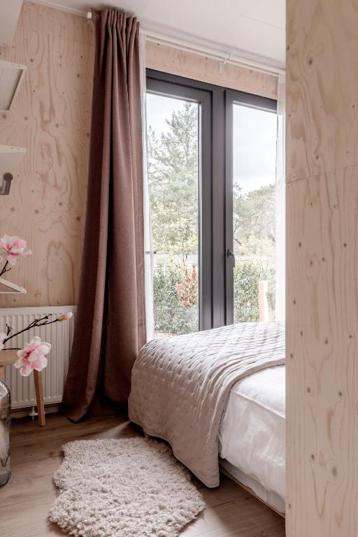 ヌンスペートにあるUltiem ontspannen in luxe en design ingericht tiny house in bosrijke omgevingのベッドルーム1室(ベッド1台、大きな窓付)