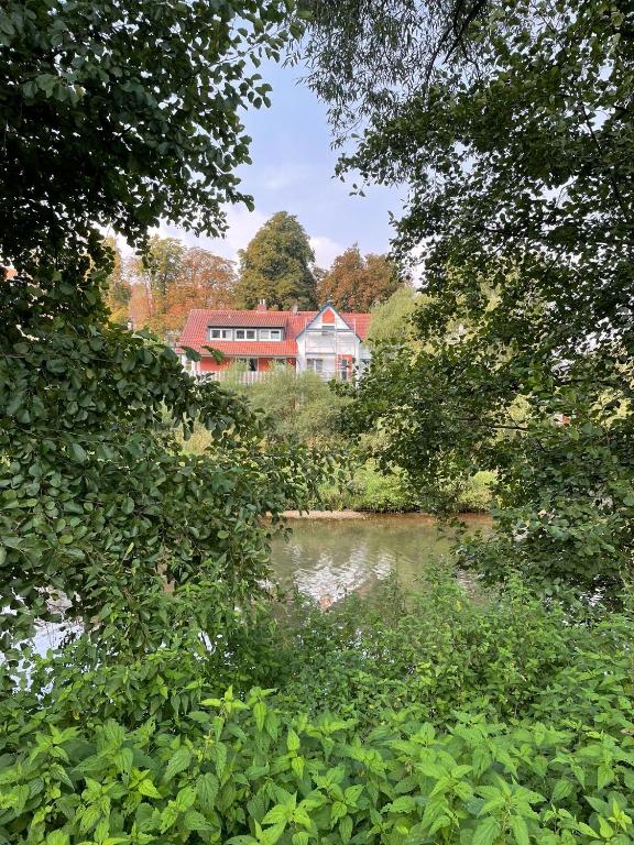 a house on a hill next to a river with trees at Ferienwohnung Diemelblick in Trendelburg