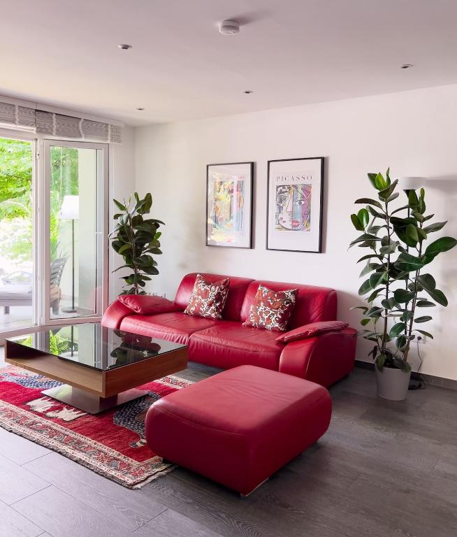 a living room with a red couch and a table at Waterfront Apartment am Main, 15 Min Frankfurt Airport, Terrasse, Free Parking in Flörsheim am Main