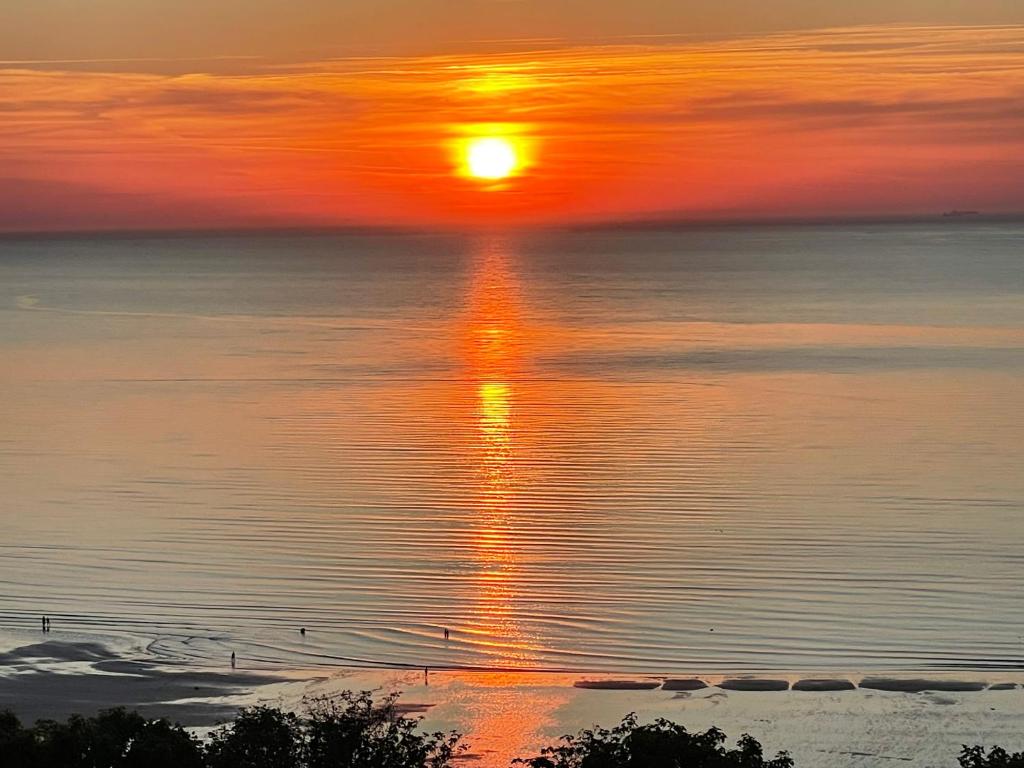 a sunset over the water with birds in the water at L'horizon de Trouville - Studio in Trouville-sur-Mer
