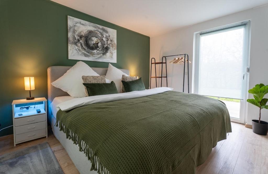 a bedroom with a large bed with a green wall at Apart79-Indust Design I Garden with Terrace I Smart TV I Free Parking I Free WiFi in Hamm