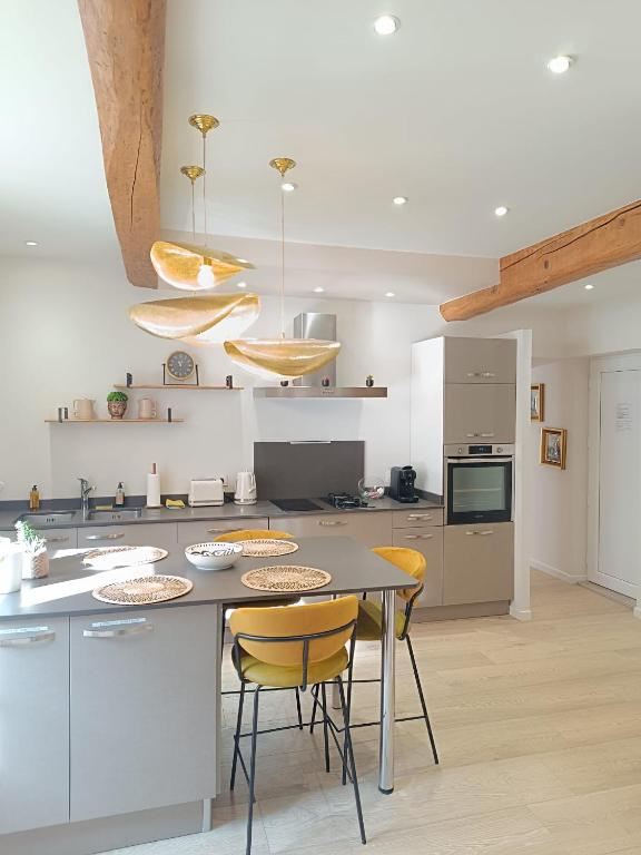 une cuisine avec une table et des chaises jaunes dans l'établissement La Nichée appartement 2 chambres, à Trévoux