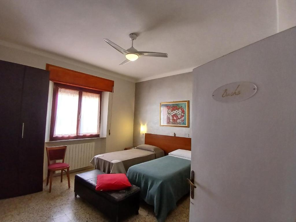 a bedroom with two beds and a ceiling fan at Hotel Signorini in Castiglioncello