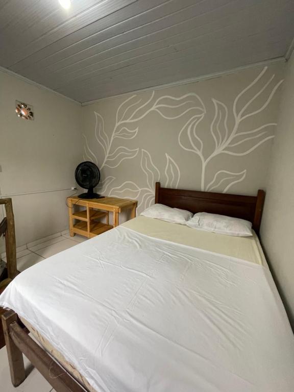 a bedroom with a bed and a wall with a tree mural at Chalé caiçara aconchegante in Paraty