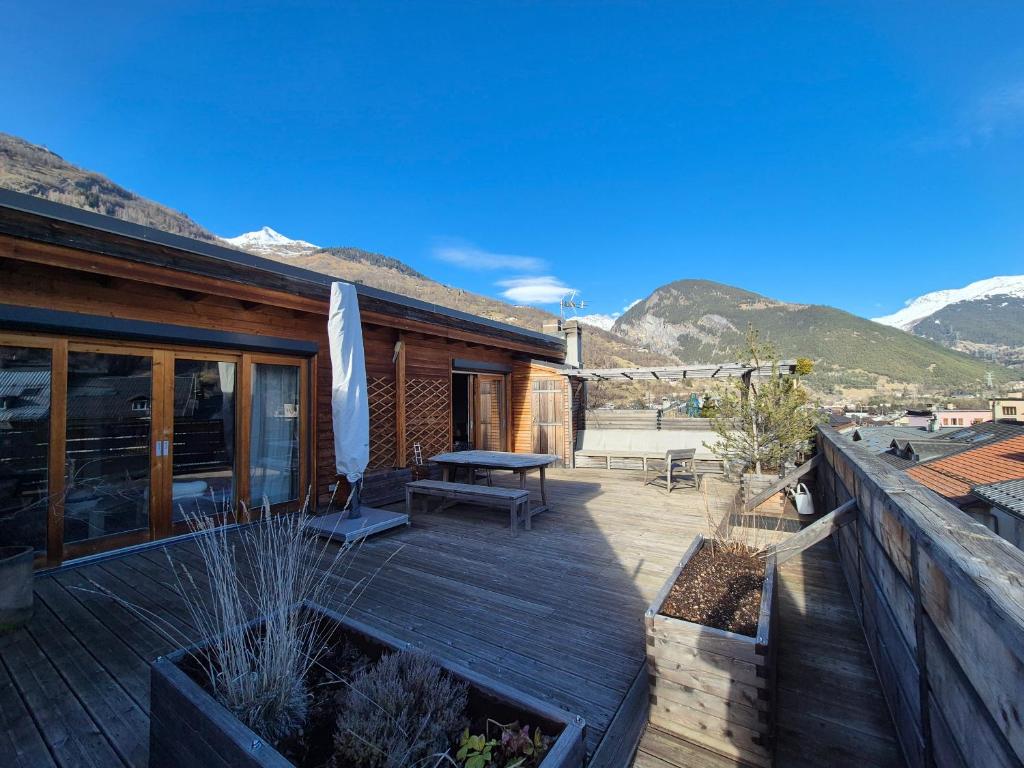 une terrasse en bois avec une table et un banc. dans l'établissement Plein centre ville, Sublime appartement avec terrasse - Bourg Saint Maurice, à Bourg-Saint-Maurice