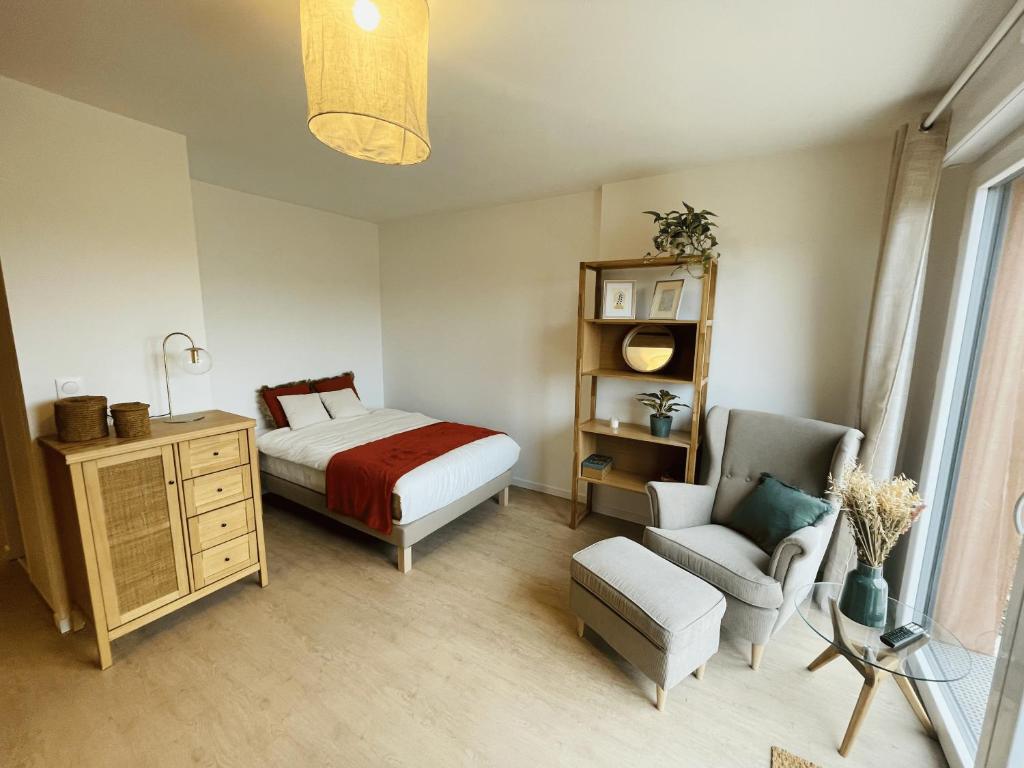 une chambre avec un lit et une chaise dans l'établissement 201 - Appartement T3 cosy, résidence calme, à Giberville