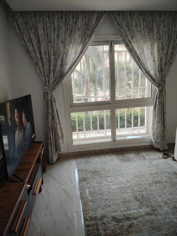a living room with a large window with curtains at Cozy Furnished apartment in new Cairo in Madinaty