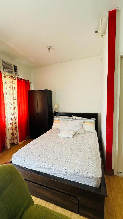 a bedroom with a large bed with red curtains at Condo unit in Novaliches Quezon City near Caloocan City in Manila