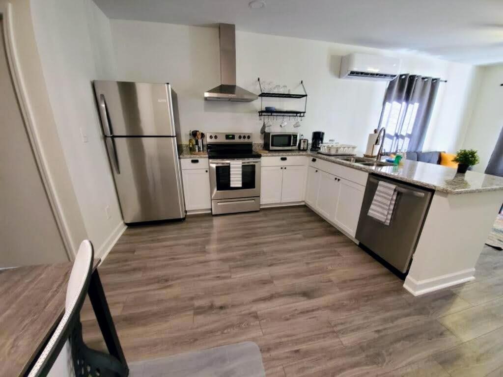 a kitchen with stainless steel appliances and a wooden floor at Lakewoodlyon Park Renovated Cottage Near Duke 26b in Durham