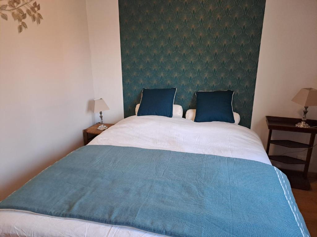 a bedroom with a large bed with two blue pillows at La Louvière plein cœur Villié-Morgon Beaujolais dégustation possible in Villié-Morgon