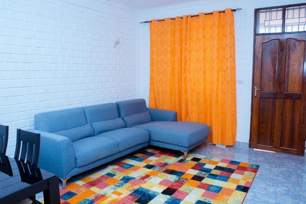 ein Wohnzimmer mit einem blauen Sofa und einem orangenen Vorhang in der Unterkunft Entire home in Mlole, Kigoma, Tanzania in Gungu
