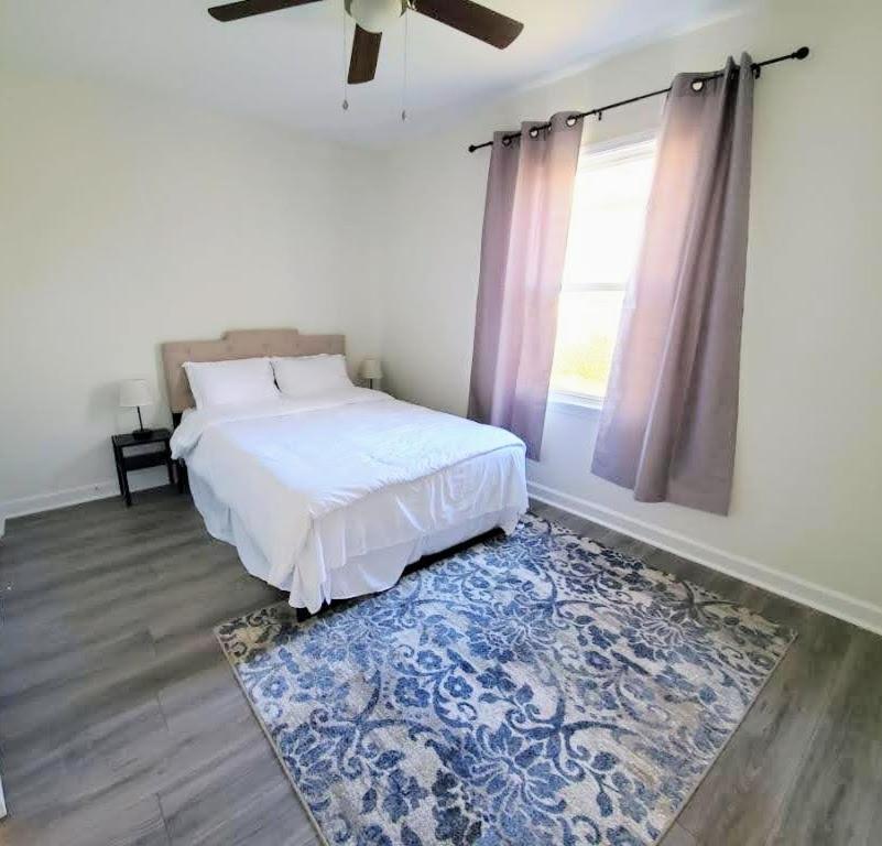 ein Schlafzimmer mit einem Bett mit einem blauen Teppich und einem Fenster in der Unterkunft Lakewoodlyon Park Renovated Cottage Near Duke 28a in Durham