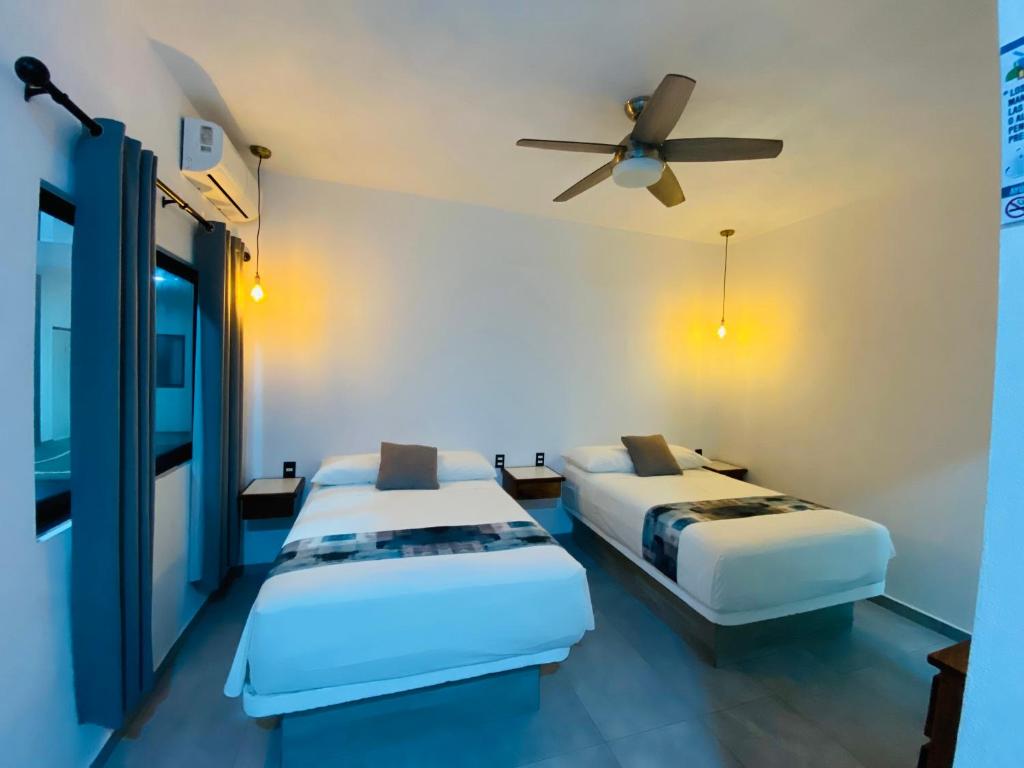 two beds in a room with a ceiling fan at Hotel Boutique Manta in Los Ayala