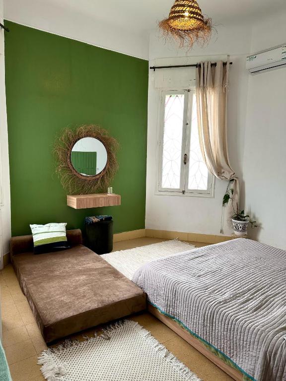 a green bedroom with a bed and a mirror at Nomads Hostel Tunisia in Tunis
