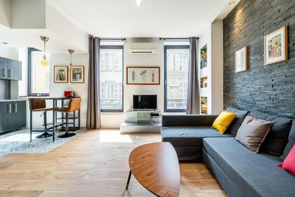 un salon avec un canapé et un mur de briques dans l'établissement Cosy et spacieux T2 en ville - paradis centre-ville, à Marseille