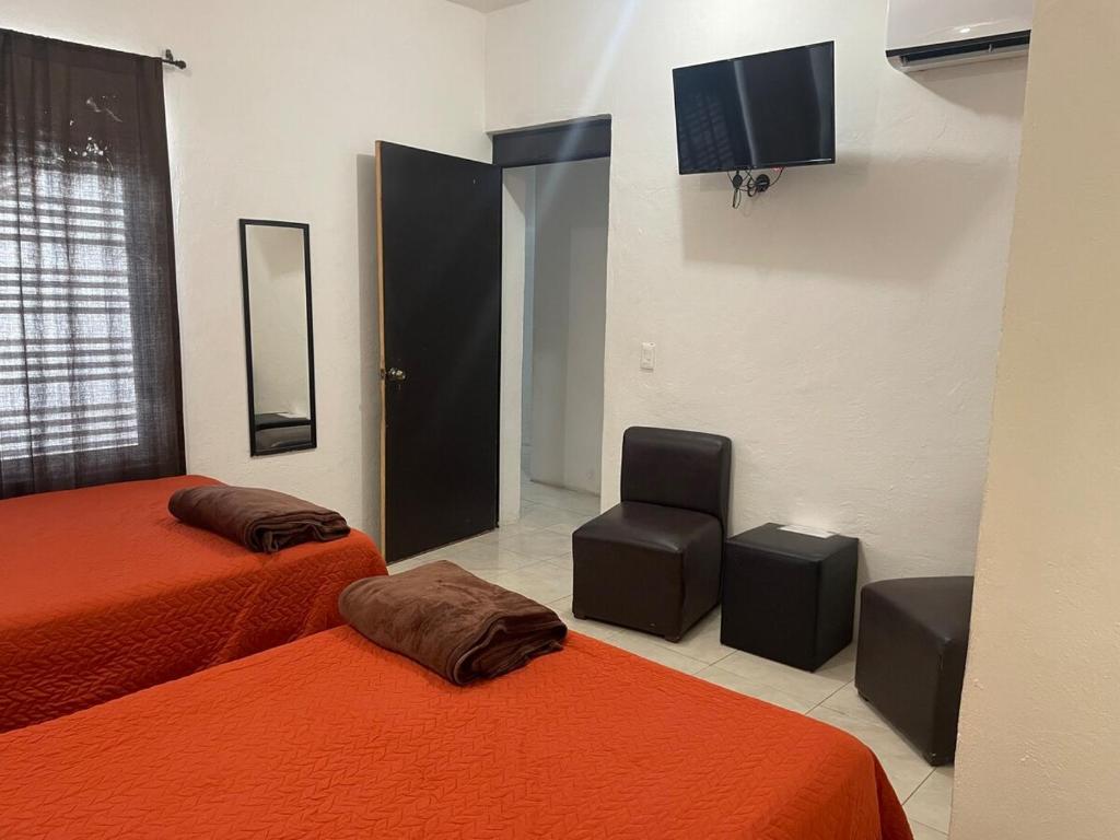 Cette chambre comprend deux lits, une chaise et une télévision. dans l'établissement La Quinta Perez, à Huay Pix