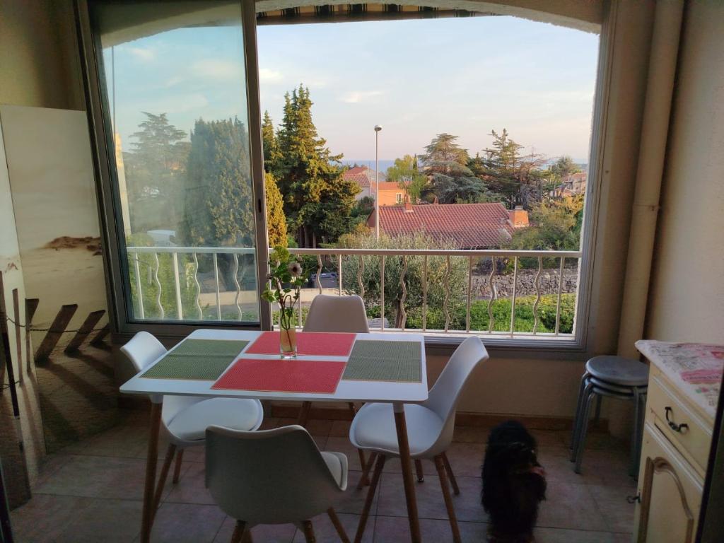 - une table et des chaises dans une cuisine avec une grande fenêtre dans l'établissement Appartement vue mer, à Bandol