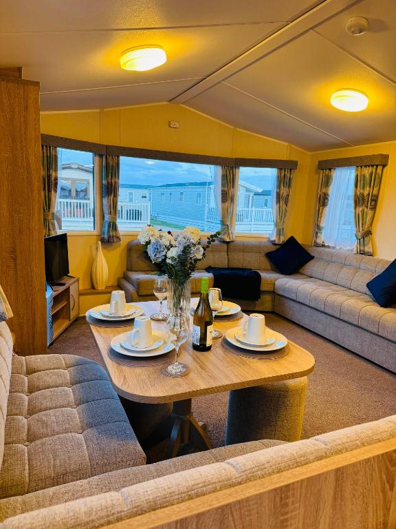 a living room with a table and a couch at Little Cha-Am Caravan Hire at Silver Sands in Lossiemouth