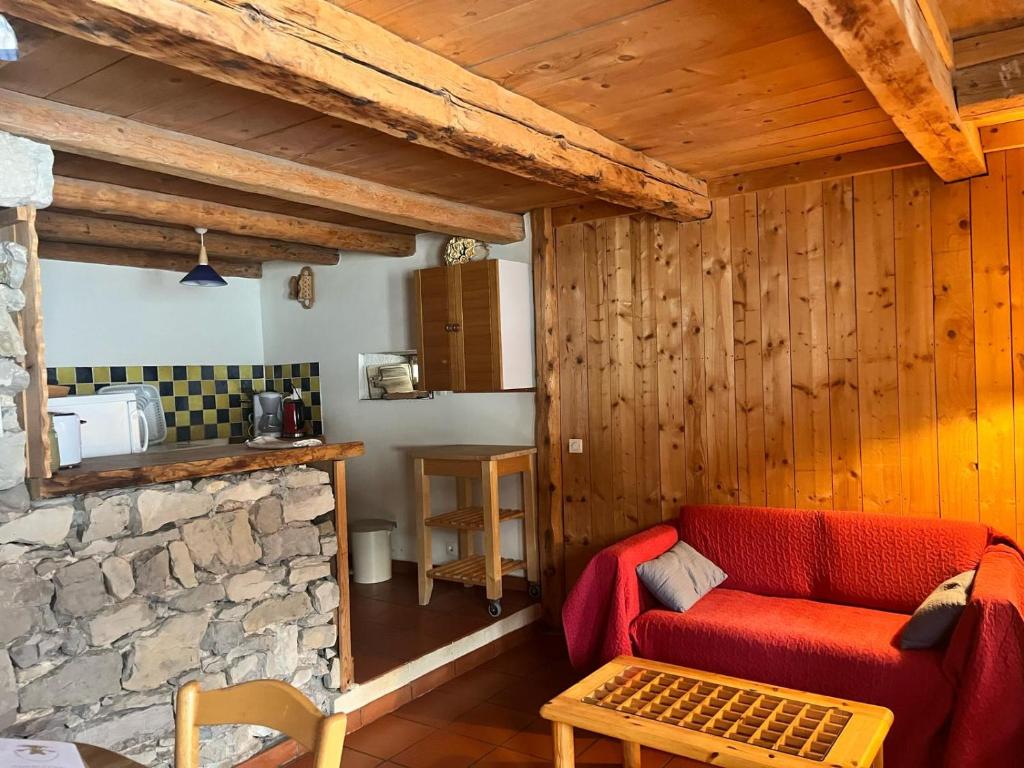 sala de estar con sofá rojo y pared de piedra en Gîte rural le four à pain dans le parc naturel du Haut Jura, en La Pesse