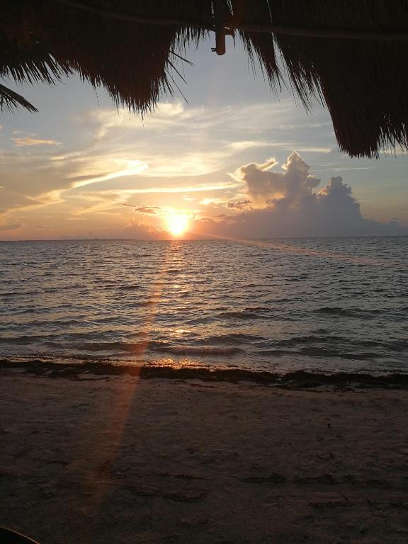 a sunset on the beach with the sun setting over the ocean at Cancun Condo & Resort in Cancún