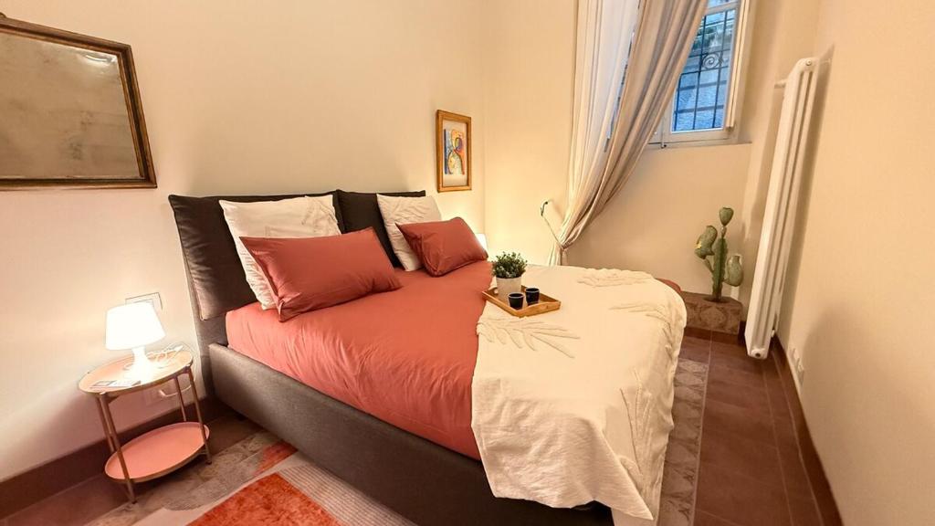 ein Schlafzimmer mit einem Bett mit roten Kissen und einem Fenster in der Unterkunft Residenza Palazzo Gherardi in Parma