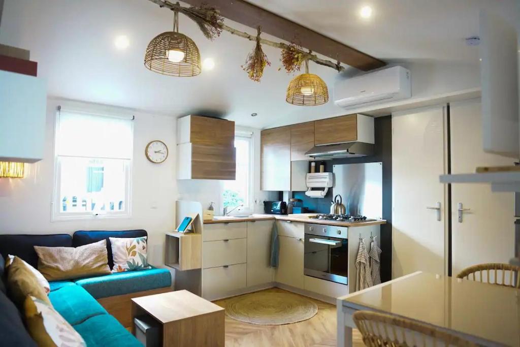- une cuisine et un salon avec un canapé bleu dans la chambre dans l'établissement Fare iti Les Viviers Lège Cap-Ferret, avec climatisation, à Lège-Cap-Ferret