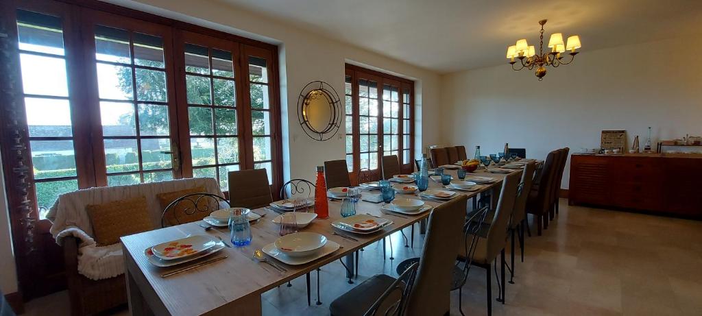 długi stół w pokoju z krzesłami i oknami w obiekcie Villa Maëlla - 2 gîtes - jardin, piscine et SPA privés w mieście Saint-Michel-Tubœuf