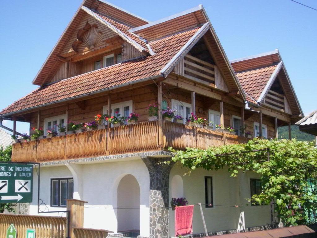 a house with a wooden roof and a balcony at Casa Muntean in Vadu Izei