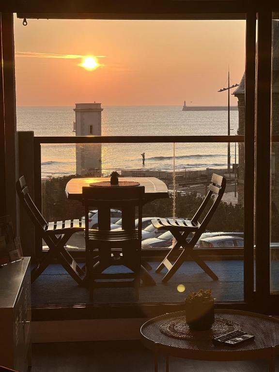 - un balcon avec une table et des chaises offrant une vue sur l'océan dans l'établissement Les Deux Phares, à Les Sables-dʼOlonne