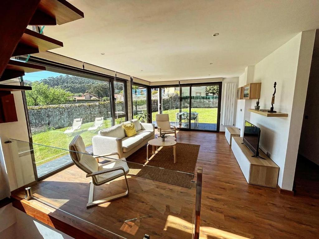 a living room filled with furniture and a large window at Casa El Lloréu in Naves