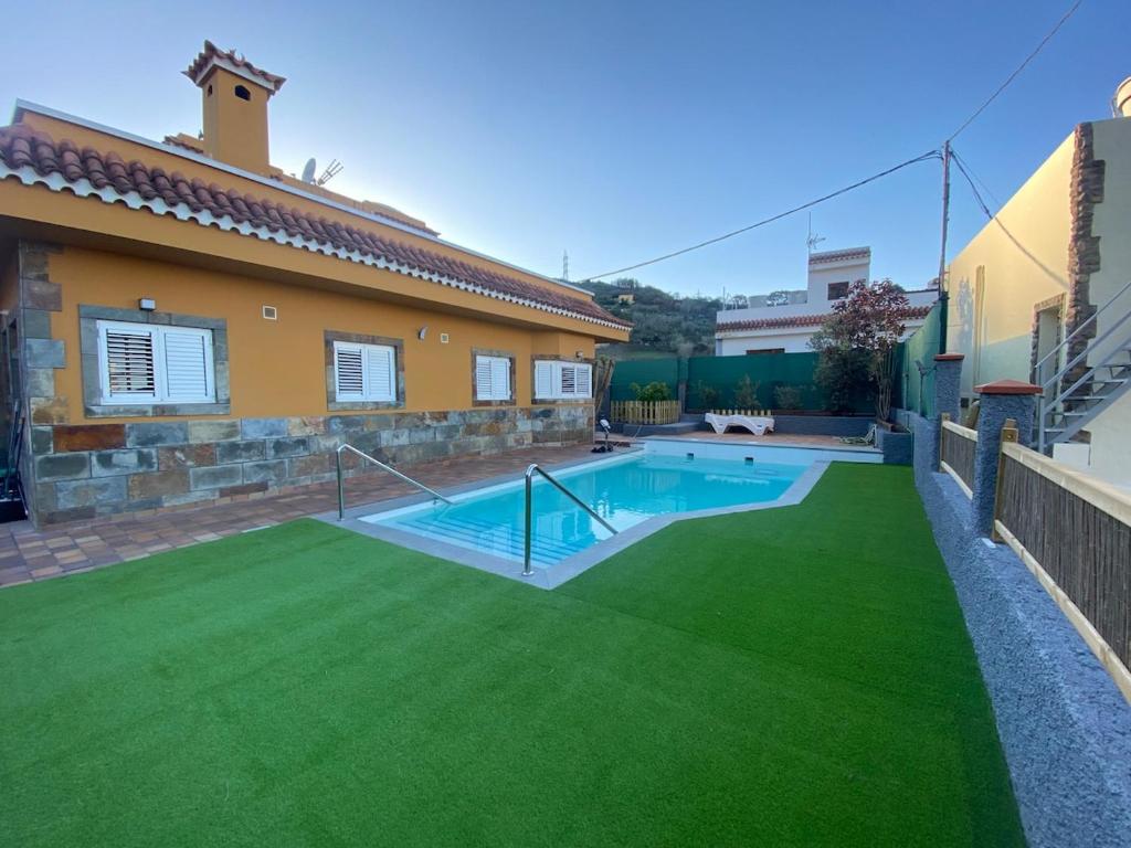 a backyard with a swimming pool and green grass at El Álamo, tranquilidad y naturaleza in Teror