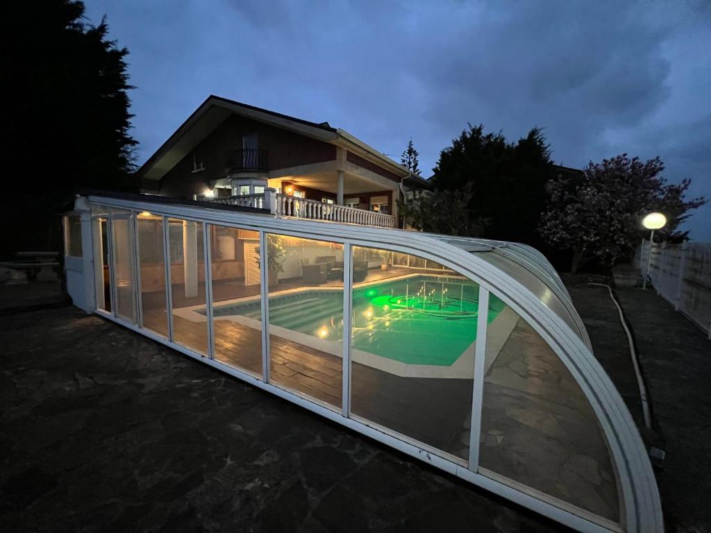 a glass house with a swimming pool at night at VILLA OSTRERA in Suances
