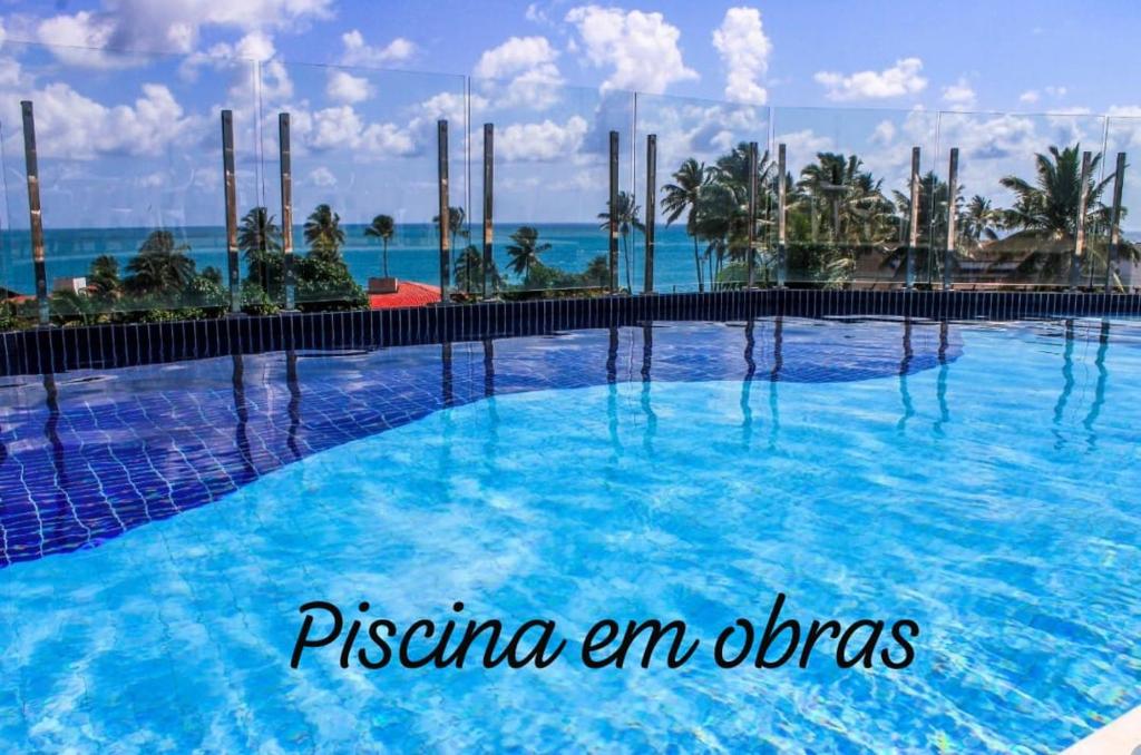 une piscine avec l'océan en arrière-plan dans l'établissement Makaiba Residence 203, à Porto de Galinhas