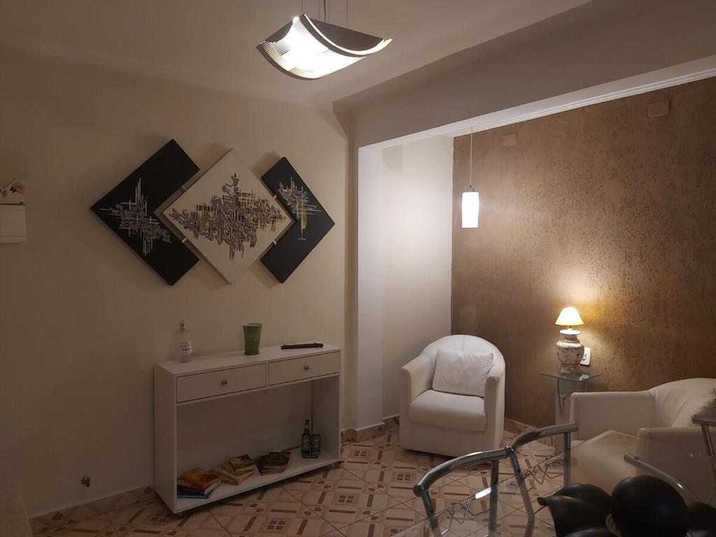 a living room with a white chair and a table at Apê Junsam in Sao Paulo