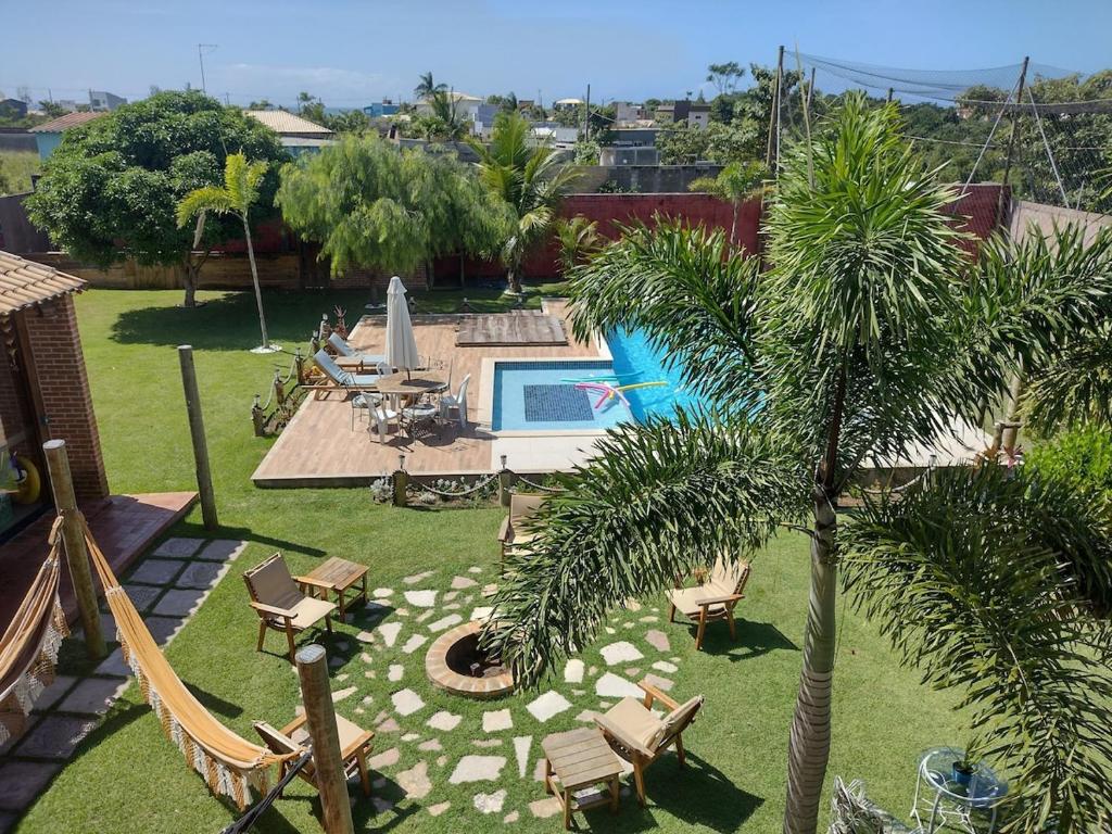 a backyard with a pool and a palm tree at Casa Amarela Praia Grande in Fundão