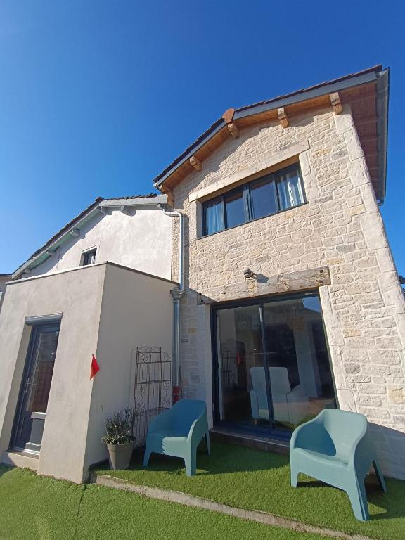 une maison avec deux chaises bleues devant elle dans l'établissement Grande Maison familiale proche de Lyon 7 personnes, à Dommartin