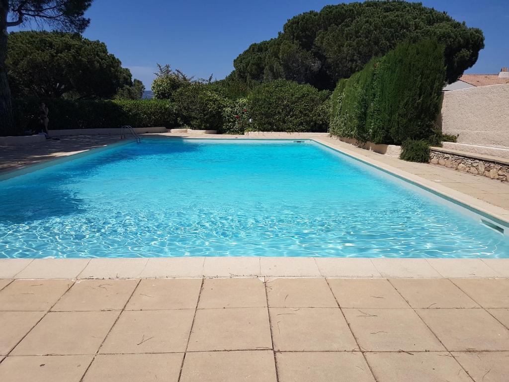 une grande piscine bleue avec des arbres en arrière-plan dans l'établissement Appartement duplex de standing au calme avec piscine, à Fréjus