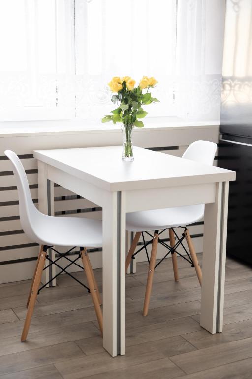 a white table with two chairs and a vase with flowers at MyPlace Caramel Apartment Sandomierz in Sandomierz