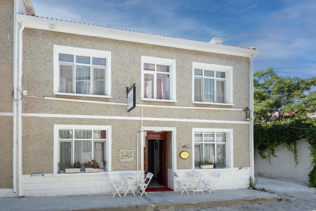 a building with a red door and white chairs at LİME BOZCAADA in Bozcaada