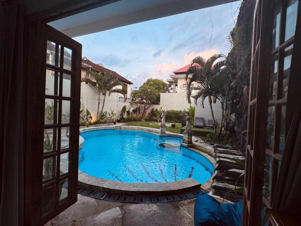 une vue d'une piscine à travers une fenêtre dans l'établissement Blue Diamond Residenses Seminyak, à Seminyak