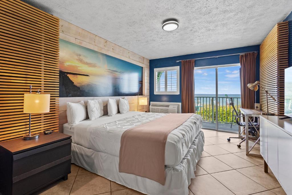 a bedroom with a large bed and a balcony at Oceanfront Inn Room #17- Ocean View Balcony King Bed in Fort Pierce